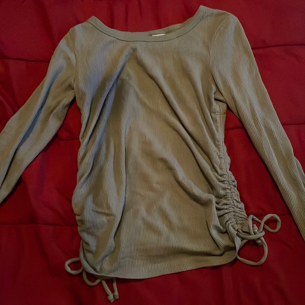 Woman’s olive green fitted long sleeve shirt with adjustable ties at hips.
